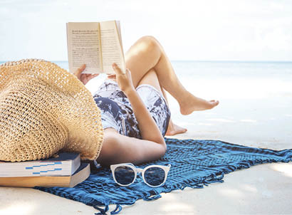 Woman reading a book on the beach in free time summer holiday