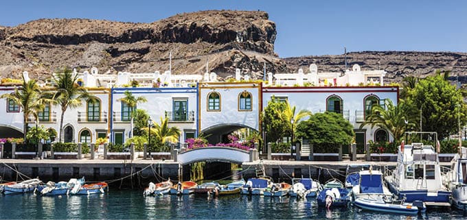  Colorful waterfront houses at the harbor of Puerto de Mogan with small motor boats, Puerto de Mogan,Gran Canaria Island, Canary Islands, Spain  