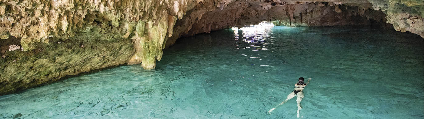 Woman swimming in freshwater Cenote in Cancun Mexico.