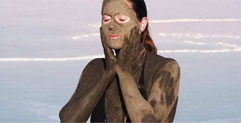 Young adult Israeli woman enjoying the natural mineral mud sourced from the dead sea, Israel  The Dead Sea known for its healthy minerals and as the lowest point on earth (1,300 feet below sea level) 