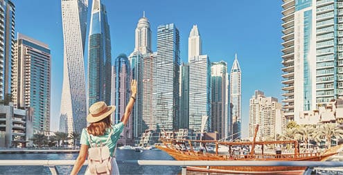 Cheerful asian traveler girl walking on a promenade in Dubai Marina district  Travel destinations and tourist lifestyle in UAE