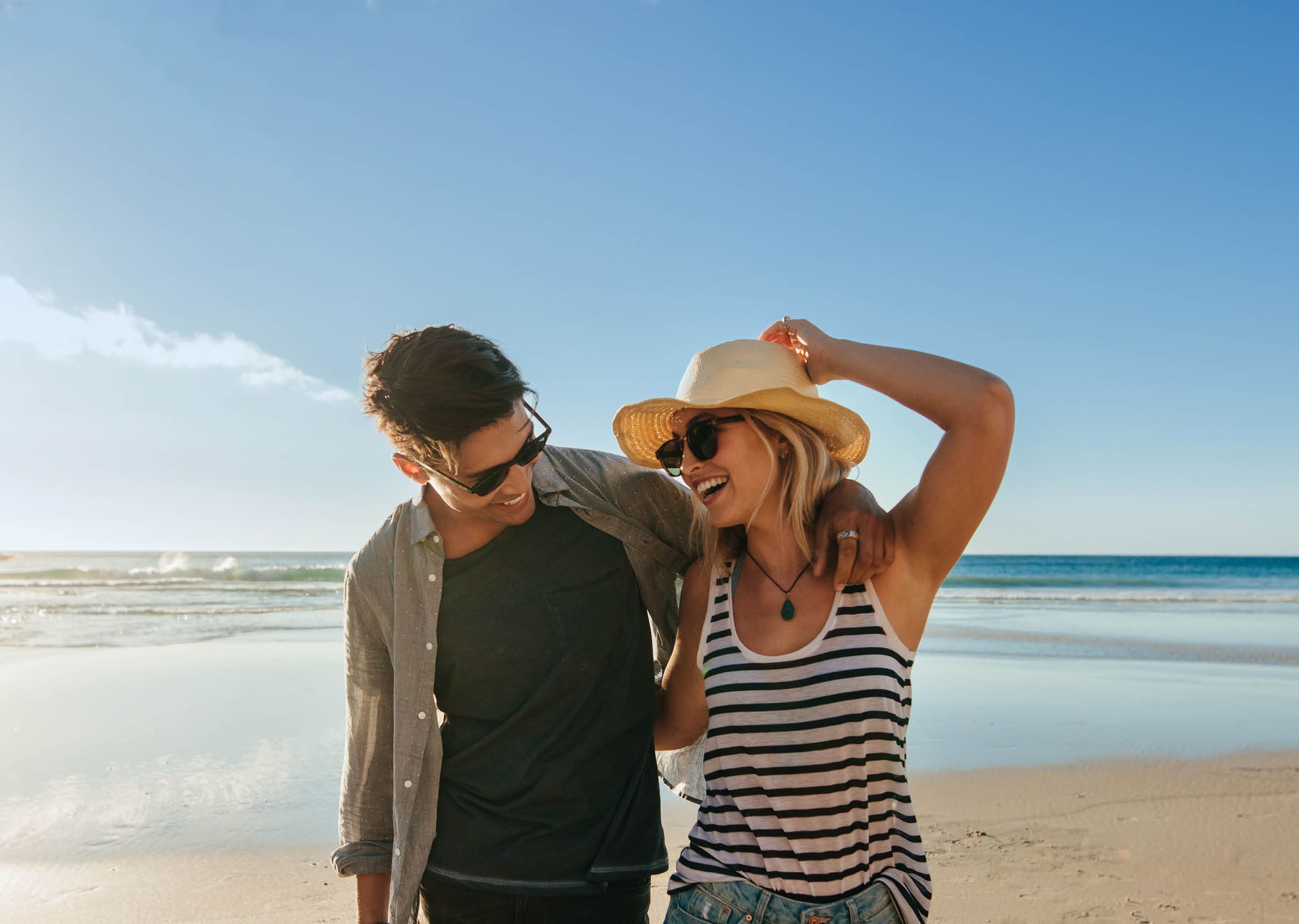 Horizontal shot of happy young couple on beach  Young man and woman walking on seashore and laughing 