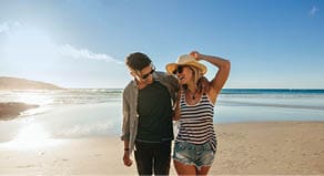 Horizontal shot of happy young couple on beach  Young man and woman walking on seashore and laughing 