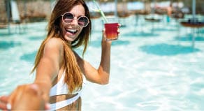 Summer vacation portrait of young woman having fun and smiling on the beach in bikini with cocktail
