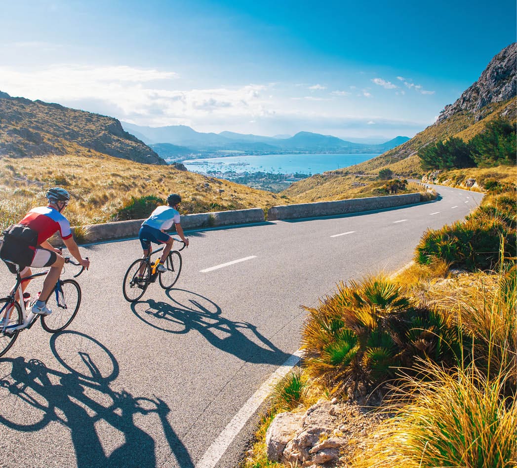 Road cycling photo  Two triathlete train in beautiful nature  Sea and mountains in background  Alcudia, Mallorca, Spain