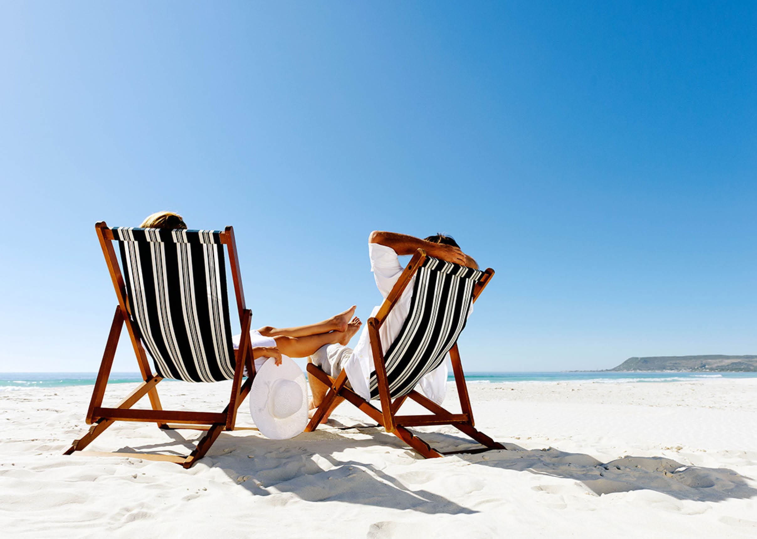 peaceful summer beach couple sitting and relaxing enjoying the sunshine on a pristine coastline