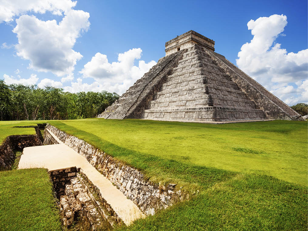 Monument of Chichen Itza on the green grass during summer in Mexico
