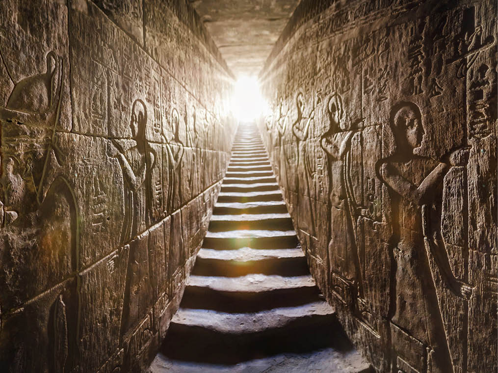 Temple of Edfu, Egypt  Passage flanked by two glowing walls full of Egyptian hieroglyphs, illuminated by a warm orange backlight from a door at the end of the stairs 