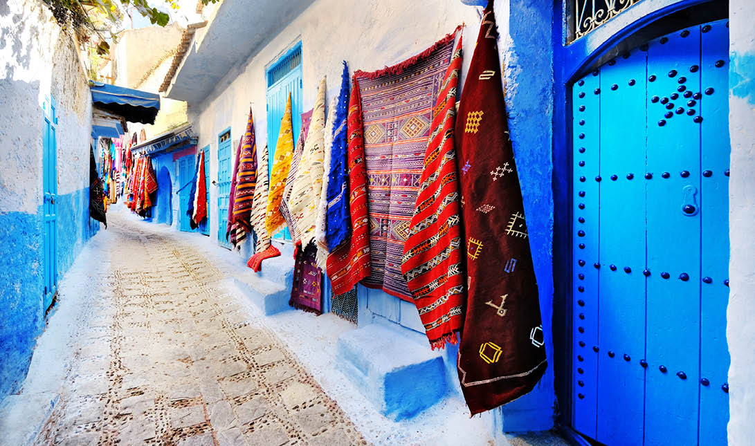 Moroccan handmade crafts, carpets and bags hanging in the narrow street of Essaouira in Morocco with selective focus