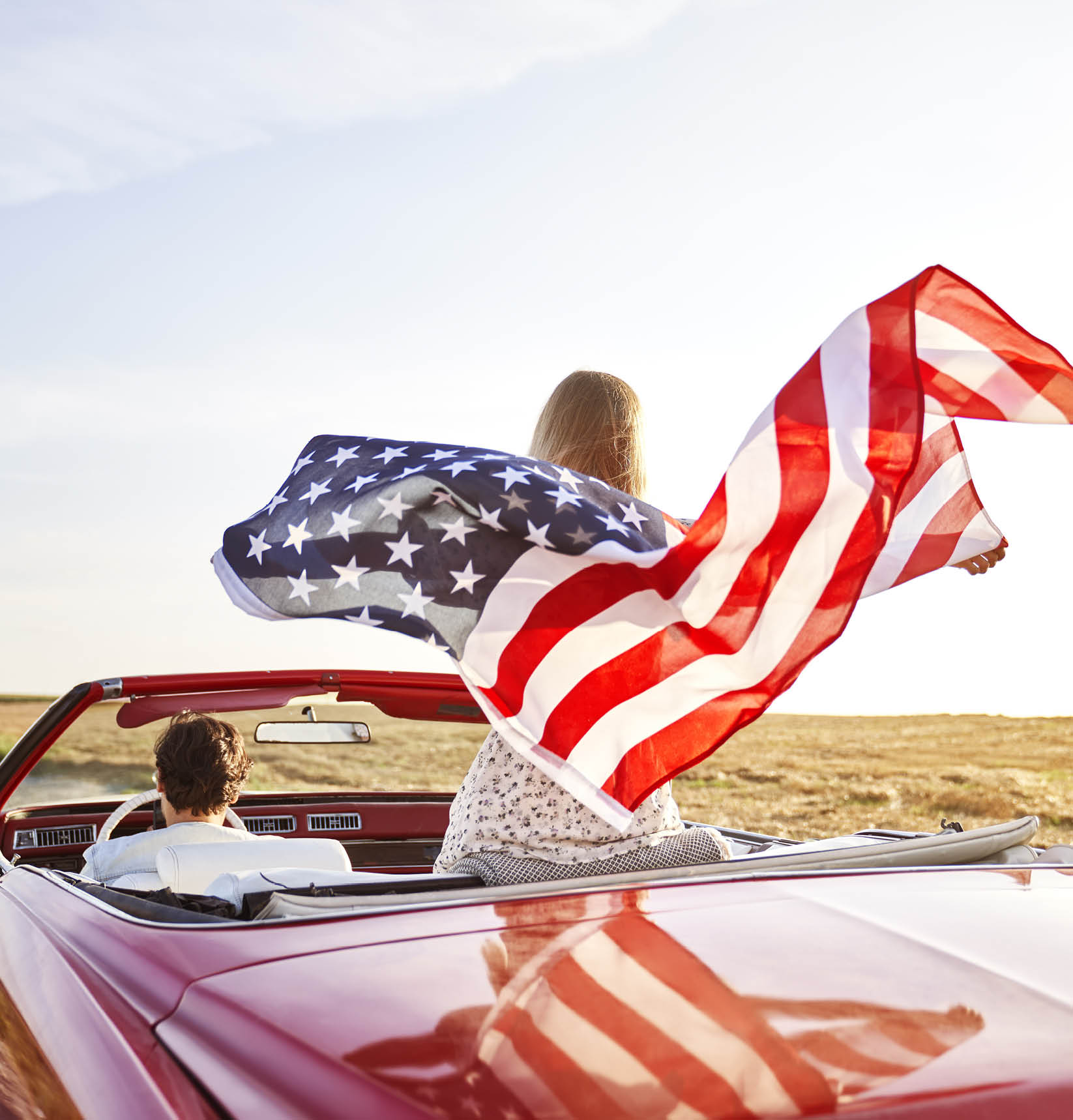 Woman holding an American flag on a road trip                                