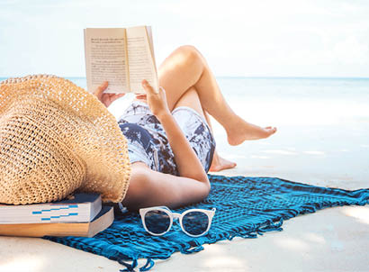 Woman reading a book on the beach in free time summer holiday