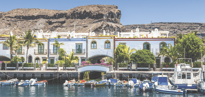“Colorful waterfront houses at the harbor of Puerto de Mogan with small motor boats, Puerto de Mogan,Gran Canaria Island, Canary Islands, Spain."