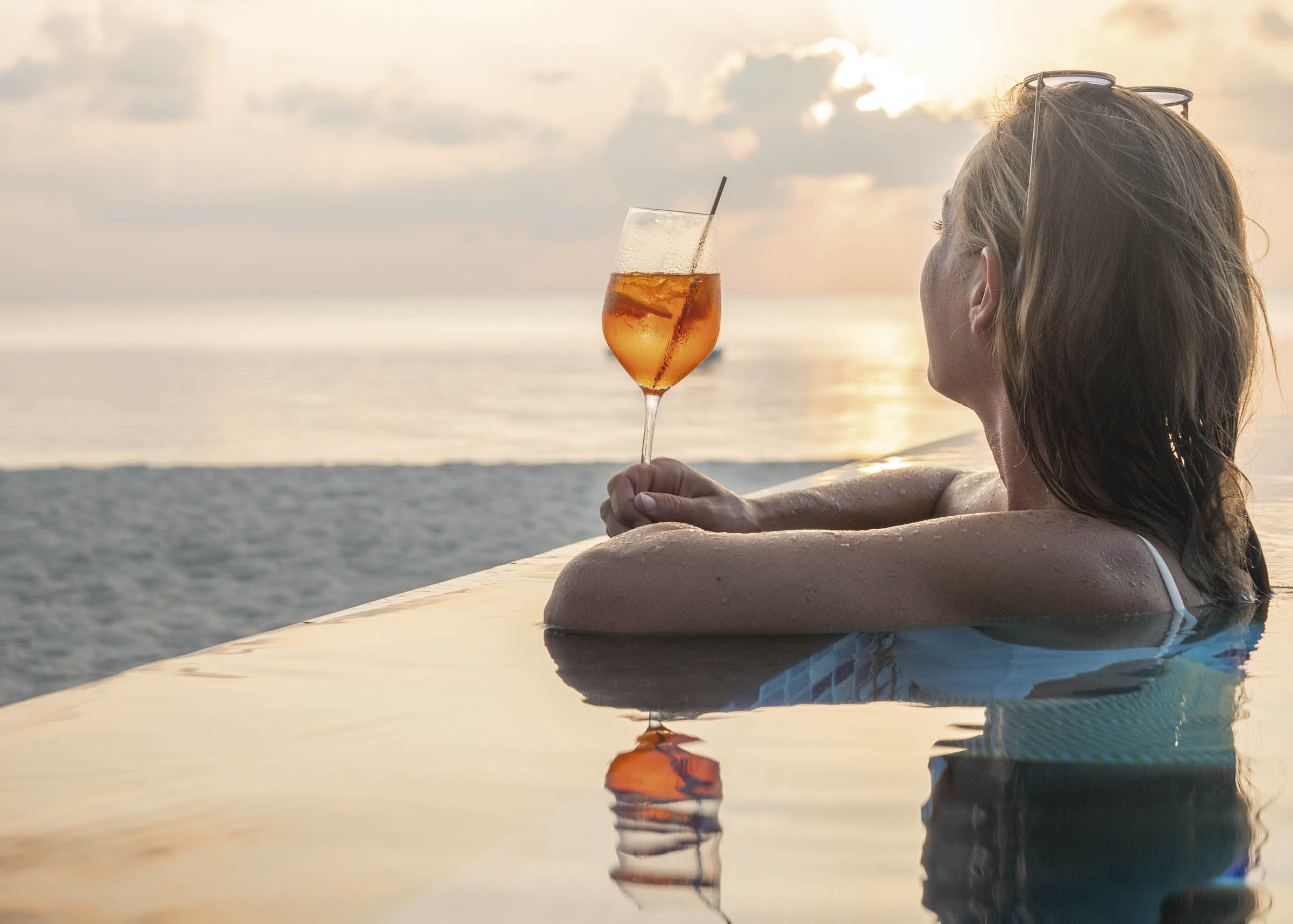 Woman on tropical beach relaxing with cocktail and enjoying sunset Luxury vacation concept