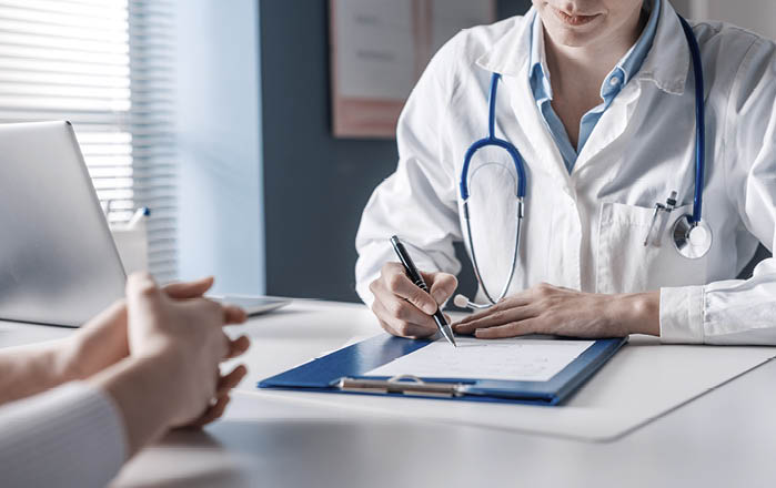 Doctor sitting at desk and writing a prescription for her patient