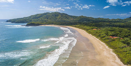Costa Rica Best Beach: Playa Grande, Guanacaste - Aerial Drone View of Tropical White Sand Beach - Famous Surfing Location with big Waves, lush green Mountains, blue Sky and beautiful Landscape.
