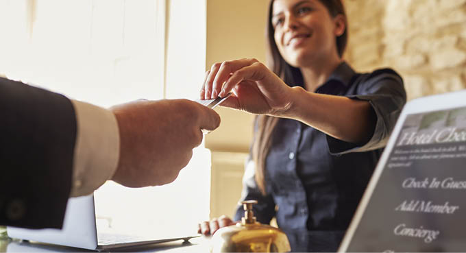 Guest takes room key card at check-in desk of hotel, close up