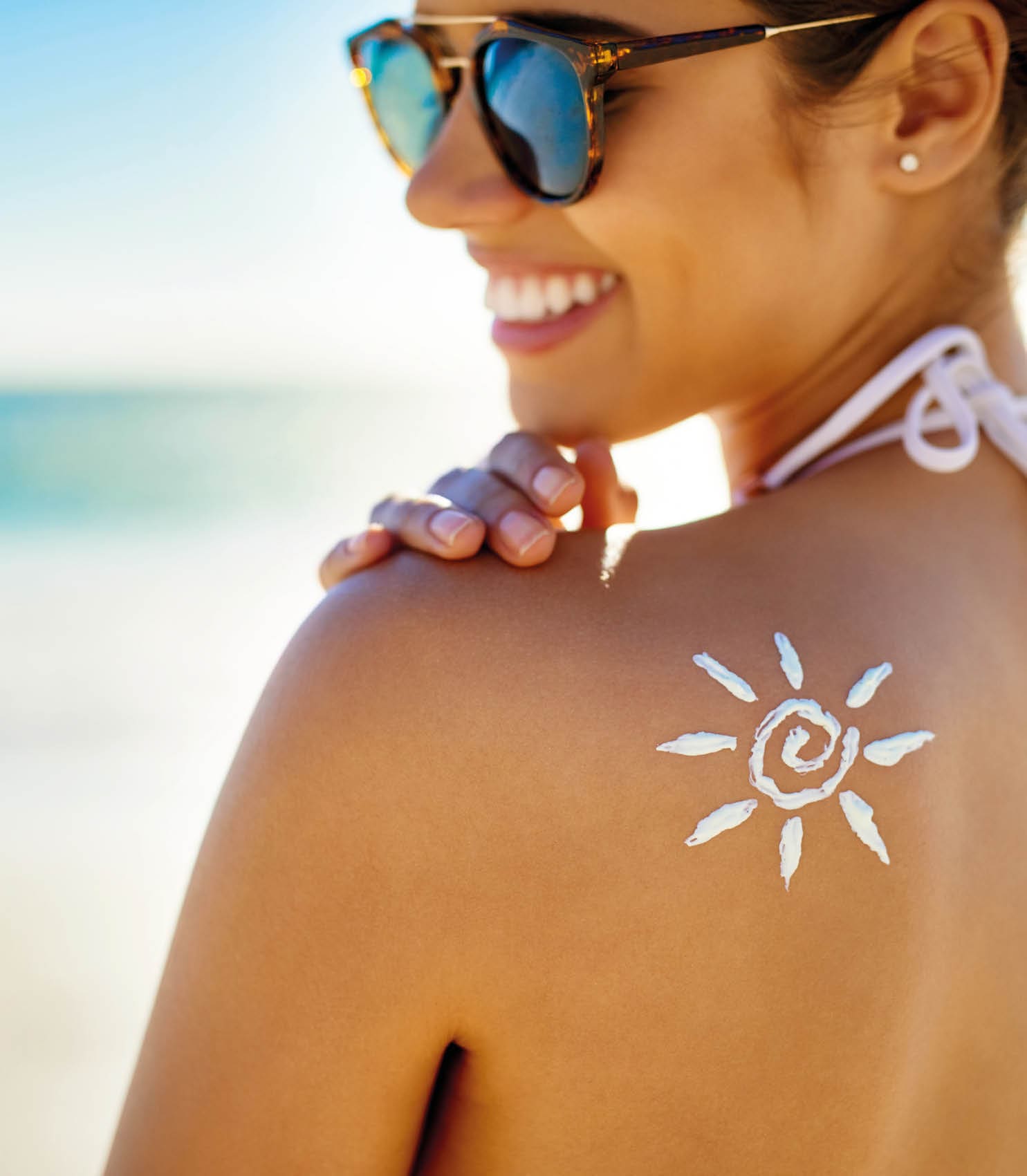 Cropped shot of a young woman posing with suntan lotion on her shoulder