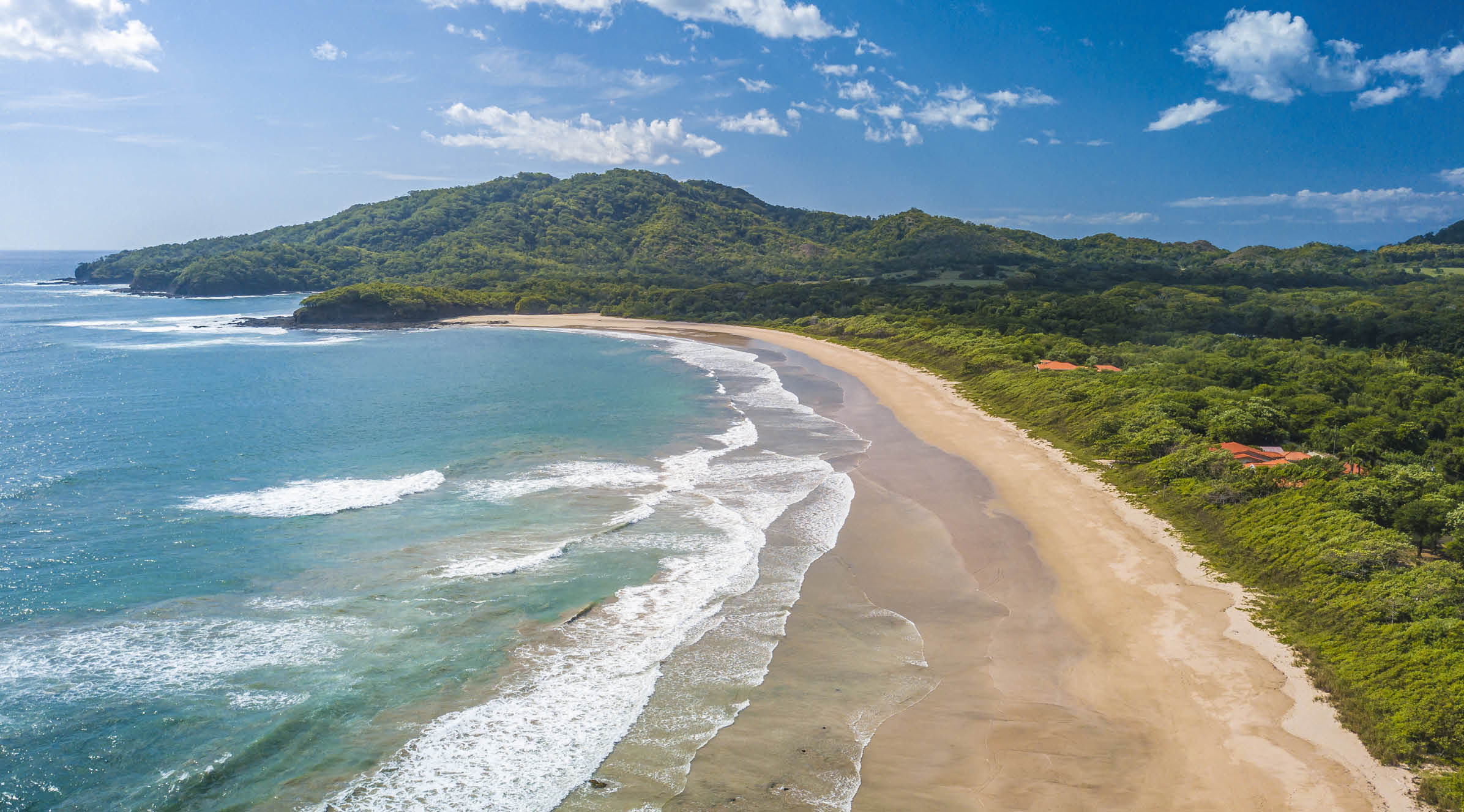 Costa Rica Best Beach: Playa Grande, Guanacaste - Aerial Drone View of Tropical White Sand Beach - Famous Surfing Location with big Waves, lush green Mountains, blue Sky and beautiful Landscape.