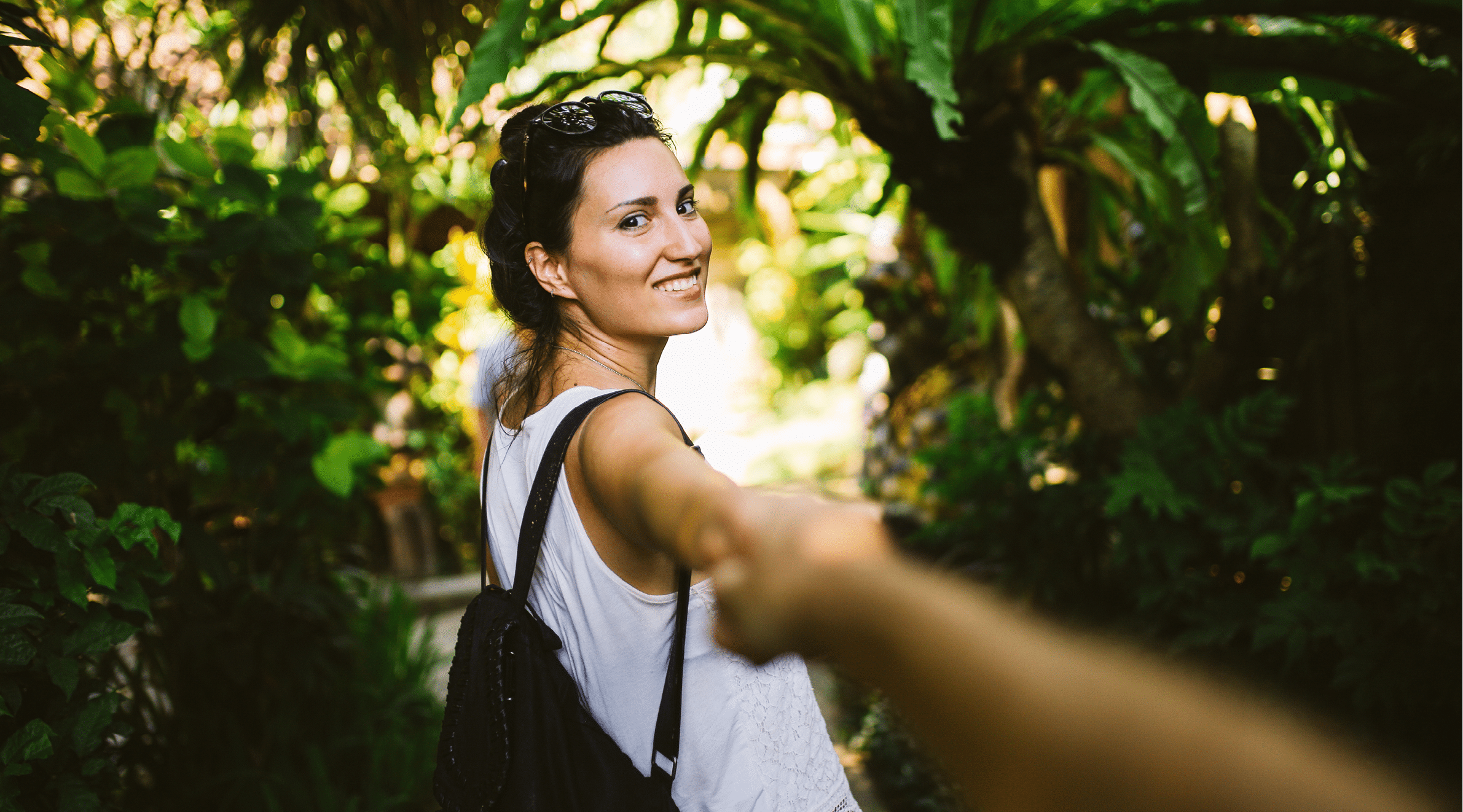 Image of a young couple walking through the tropical forest in Bali, Indonesia. She is carrying a backpack, and wearing casual yoga summertime clothing, enjoying her time on the beautiful island in the Southeast Asia.