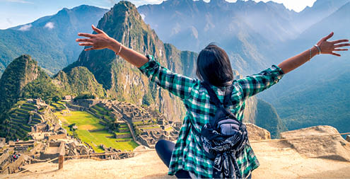 A woman tourist contemplating the amazing landscape of Machu Picchu with arms open. Archaeological site, UNESCO World Heritage