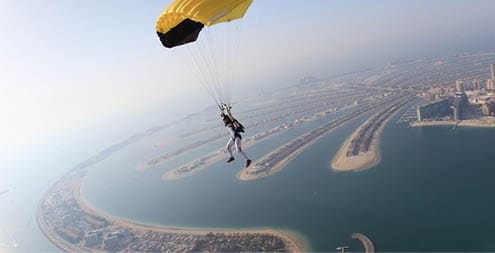 Dubai dream.Yellow extreme skydiving activity fun people on Dubai palm Jumeirah. Skydive Dubai jump travel. Yellow fun parachute jump. Summer outdoor sky activity. Big goal