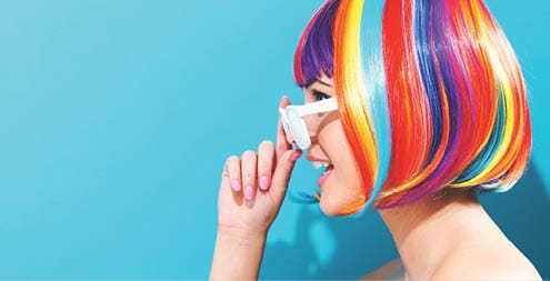 Beautiful woman in a colorful wig on a blue background