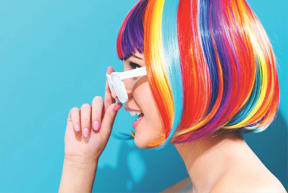 Beautiful woman in a colorful wig on a blue background
