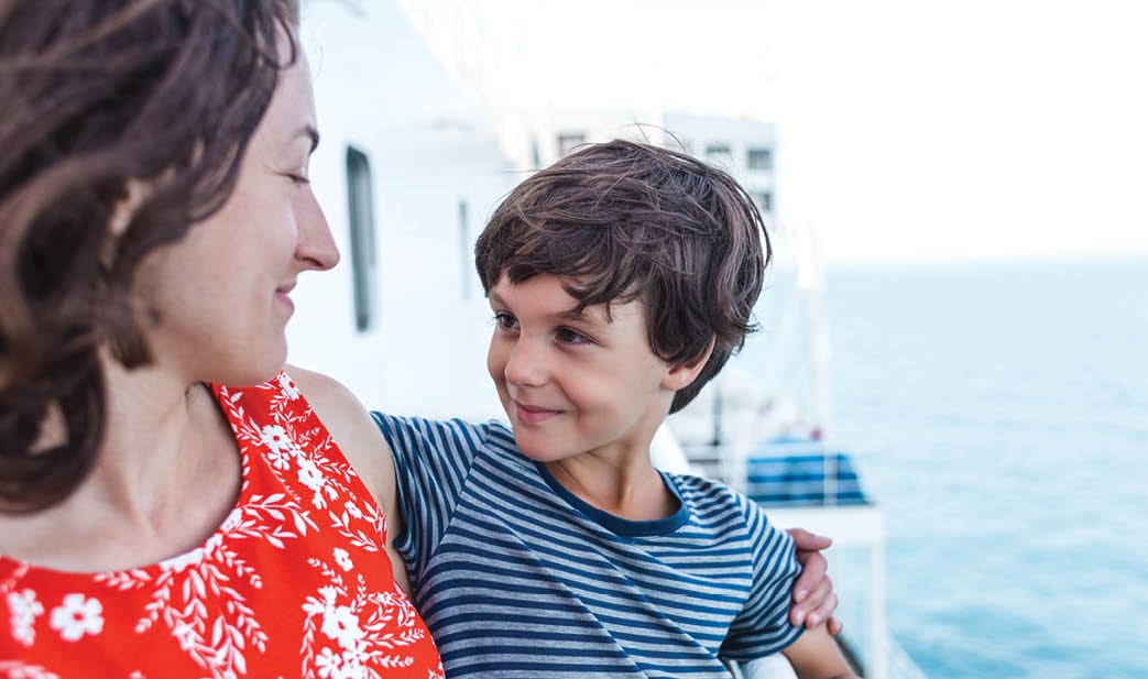 A boy and his mother stand on the deck of a ship and look at the sea, a family travels on a cruise ship, a trip across the ocean, a woman and her son look at the water 