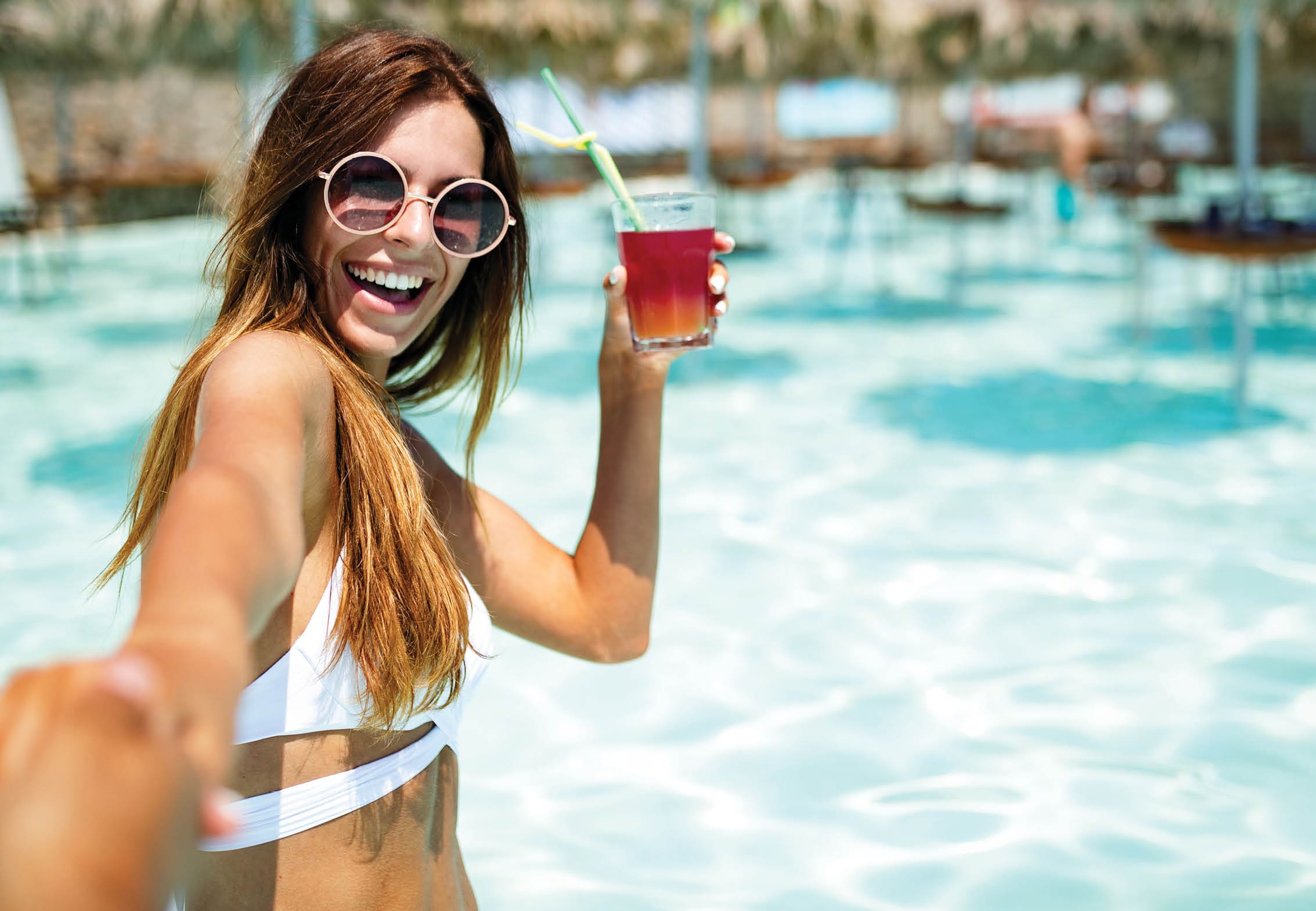 Summer vacation portrait of young woman having fun and smiling on the beach in bikini with cocktail