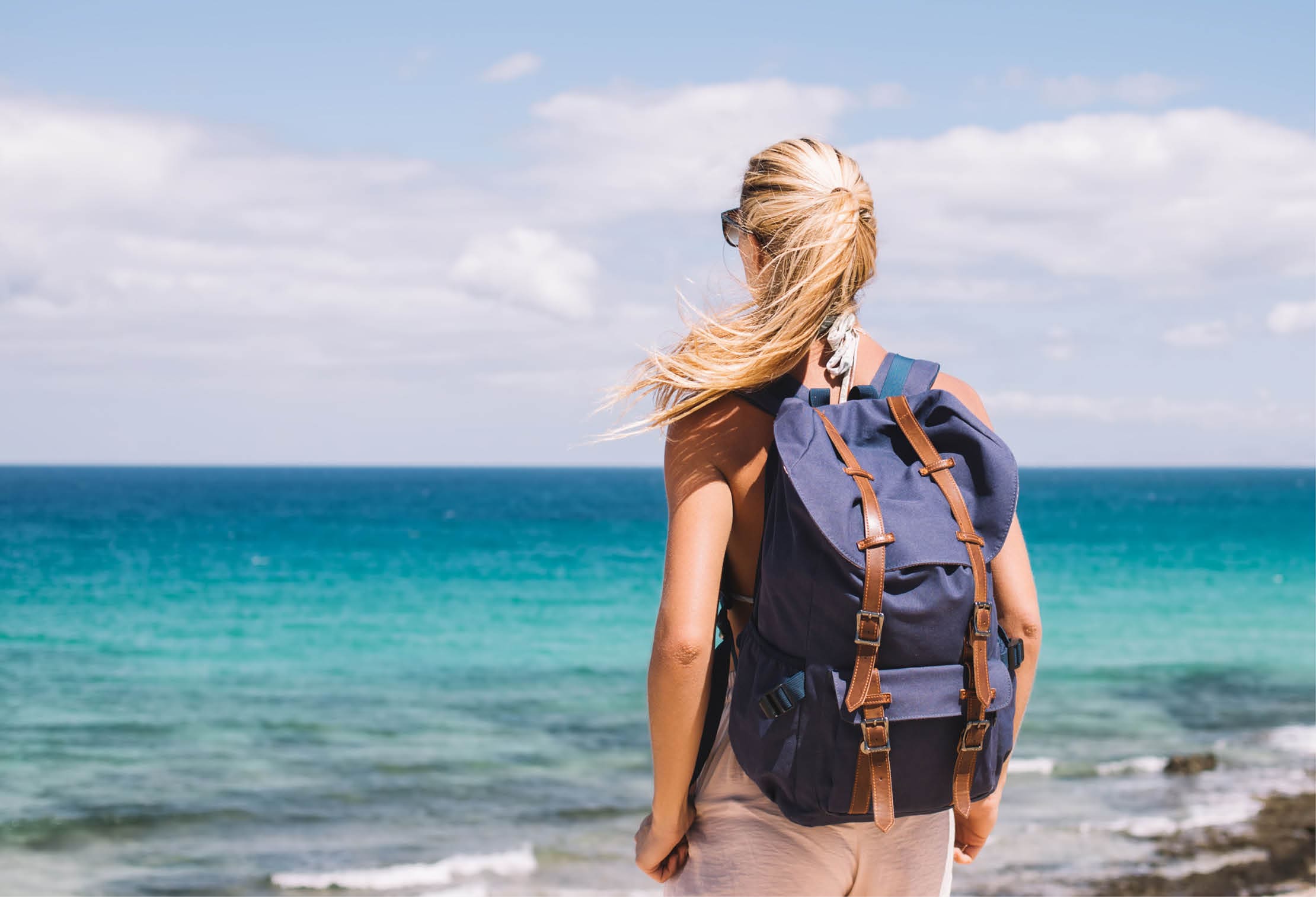 Young female traveller with touristic backpack admire seascape views enjoying summer journey trip for exploring Menorca, woman looking around of Balearic islands during solo getaway to Spain