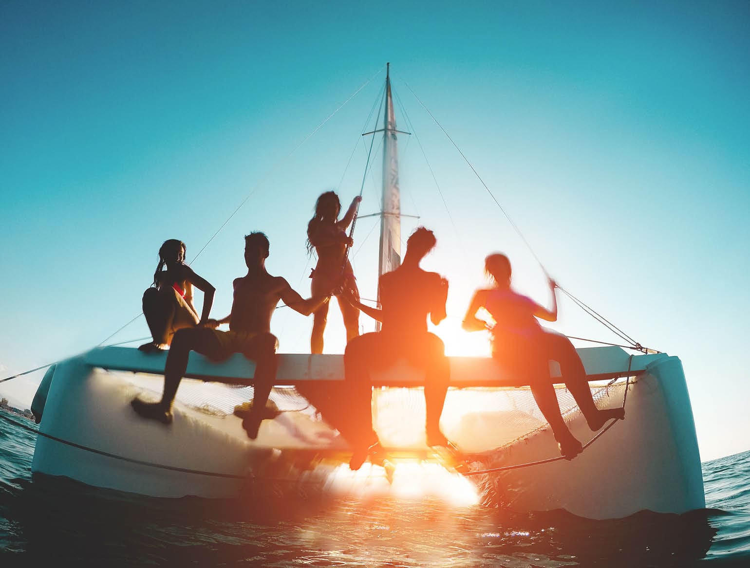 Silhouette of young friends chilling in catamaran boat - Group of people making tour ocean trip - Travel, summer, friendship, tropical concept - Focus on two left guys - Water on camera
