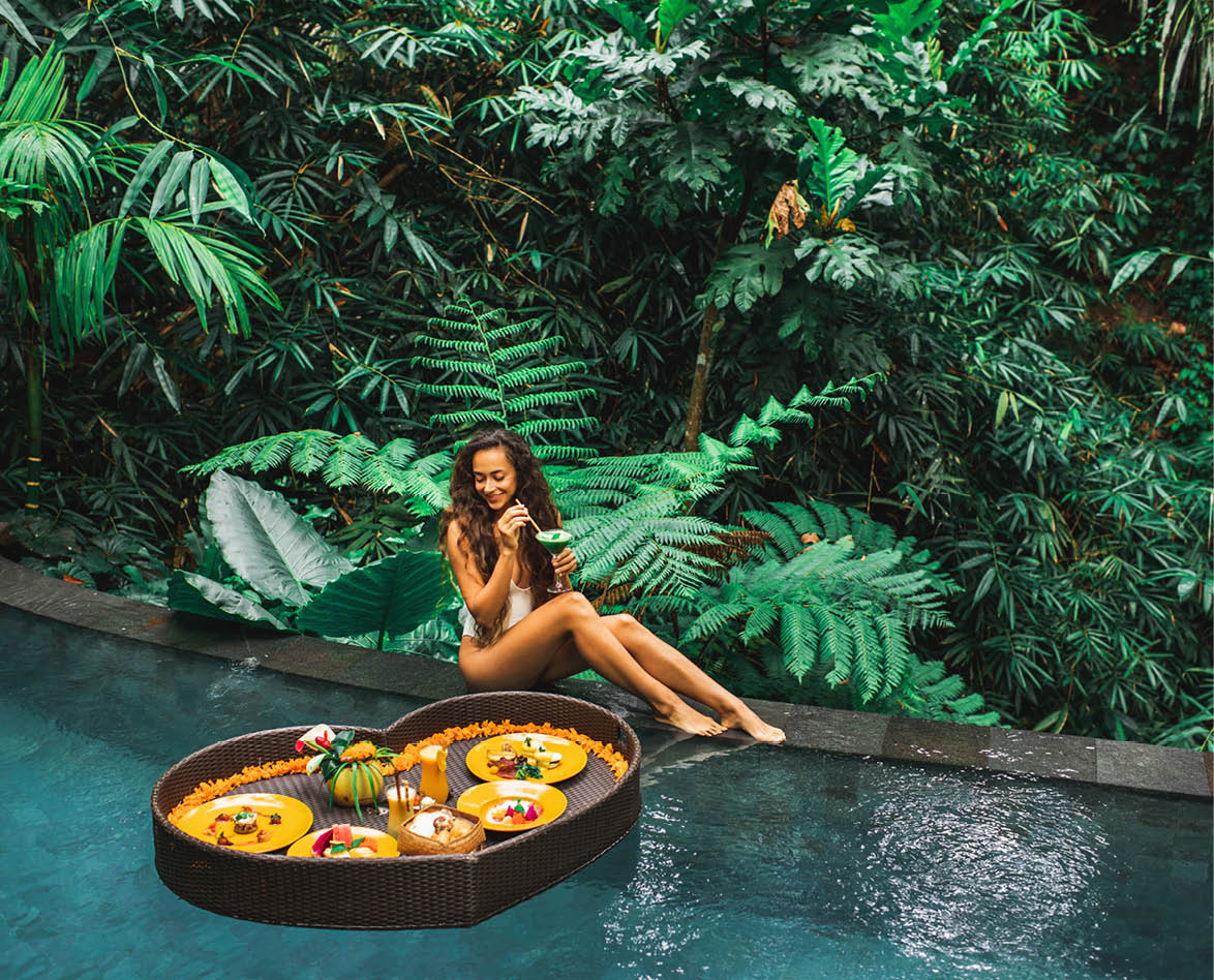 Girl relaxing and eating floating breakfast in jungle pool on luxury villa in Bali  Valentines day or honeymoon surprise  Tropical travel lifestyle  Black rattan tray in heart shape 