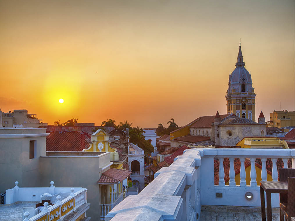 View over the rooftops of the old city of Cartagena during a vibrant sunset  The spire of Cartagena Cathedral stands tall and proud 