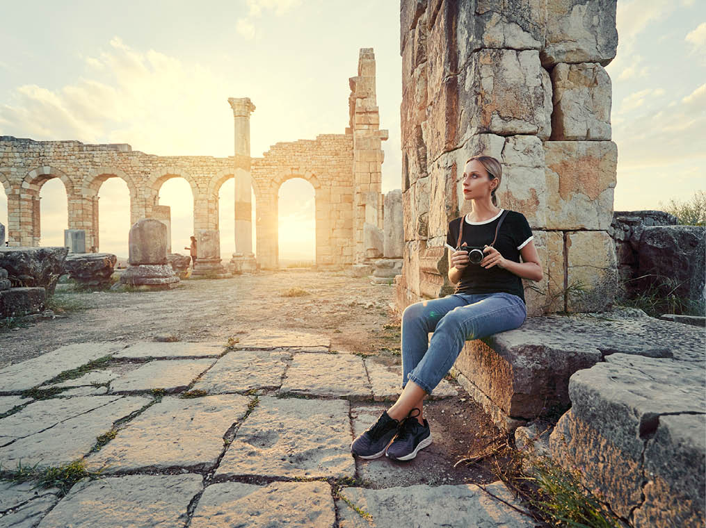 Tourism and hobby  Happy young woman taking photo of ancient antique city Volubilis  Traveling by Morocco 