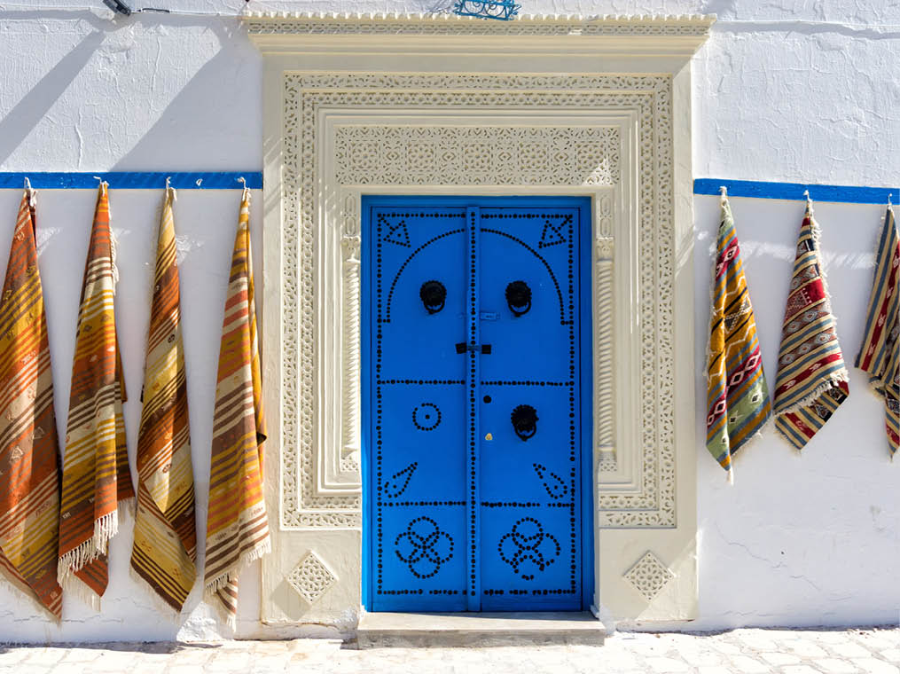 Entrance wiht colorful door and carpets for sale in Kairouan, Tunisia  