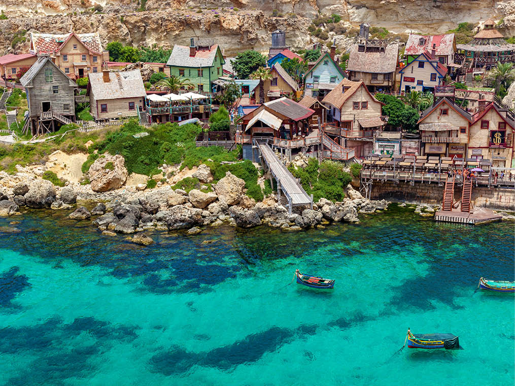 View of the famous village of Popeye with colorful wooden houses and the Gulf of Malta 