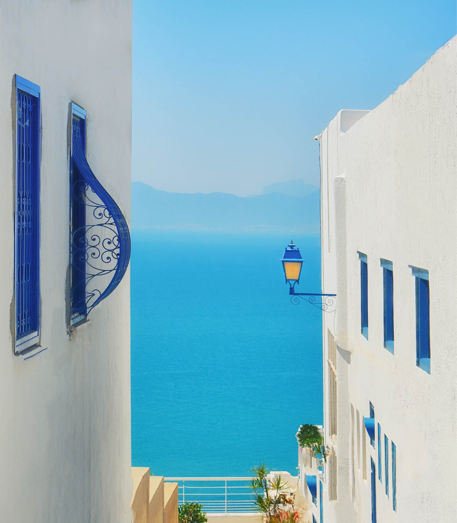 Sea and mountain views between two houses with blue windows, Sidi Bou Said, Tunisia