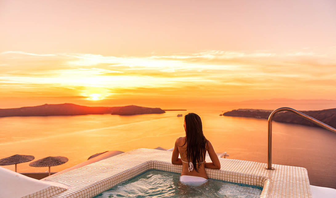 Luxury travel Santorini vacation woman swimming in hotel jacuzzi pool watching sunset  Europe resort destination holiday for honeymoon getaway 