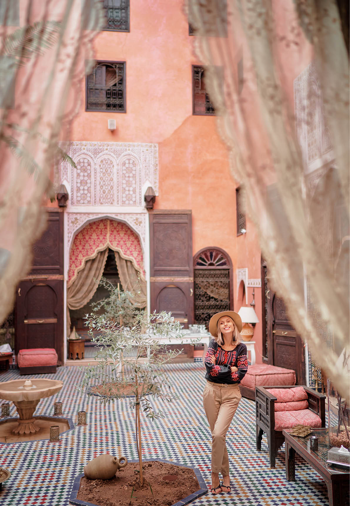Traveling by Morocco  Happy young woman in hat relaxing in traditional riad interior in medina 