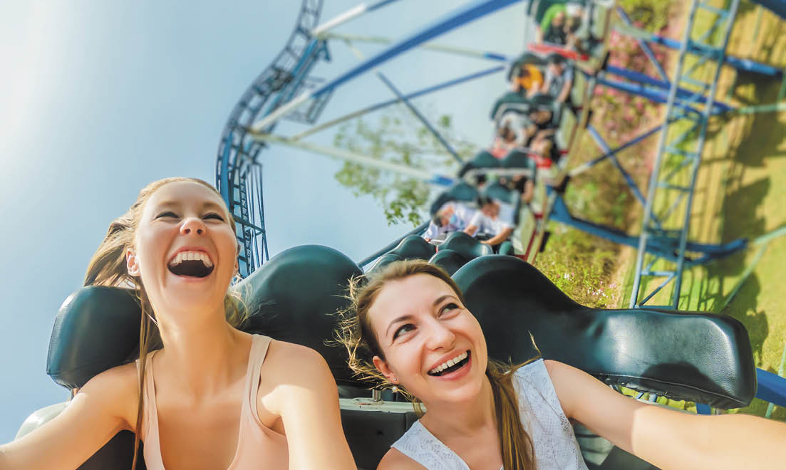 Two happy girls having fun on rollercoaster 