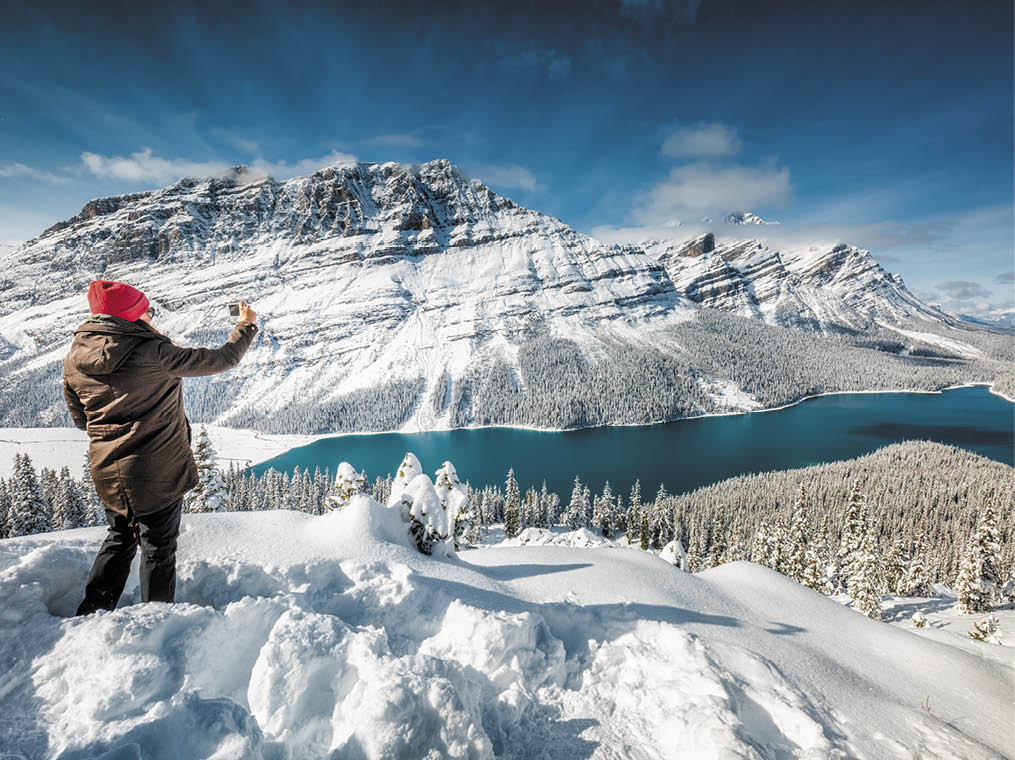 Beautiful girl with red hat taking picture with smartphone near Peyto Lake, Banff, Canada 