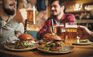 Burger with beer on the table of a group of friends in a bar pub  Hamburger on the background of people in a restaurant 