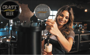 Beautiful young woman pouring beer into the glass  Female bartender tapping craft beer in bar 